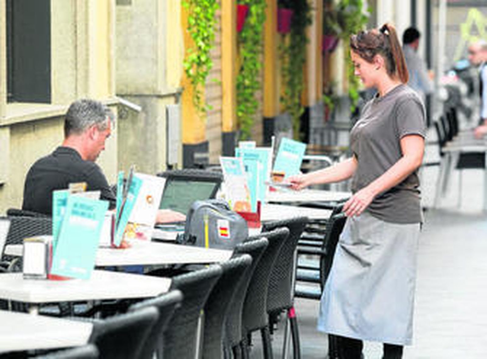 Una joven sirve un café en una zona de veladores del centro de la ciudad de Sevilla, donde han proliferado las terrazas en los últimos años.