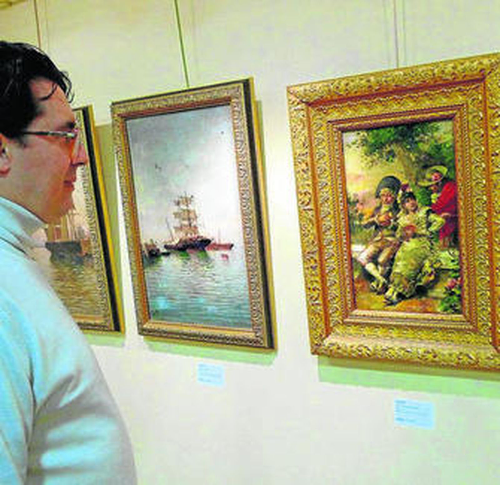 Un visitante observa algunos cuadros expuestos a subasta.