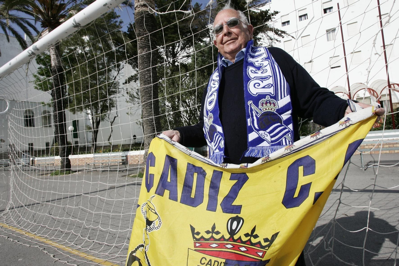 Imagen de archivo del padre Luis Castro con la bandera del Cádiz y la bufanda de la Real.