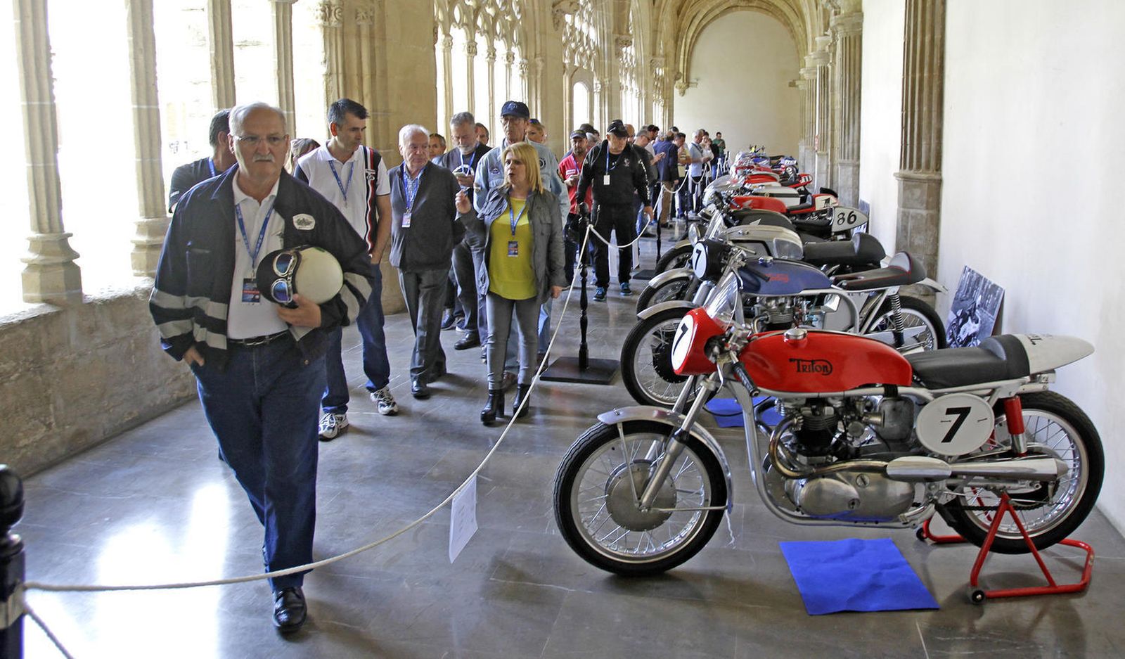 Un nutrido grupo de personas observa en los Claustros la exposición de motos clásicas.