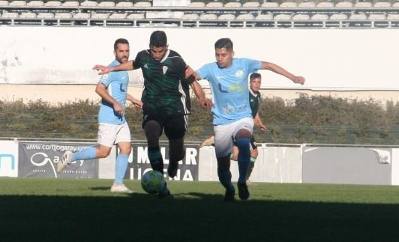 Un jugador del Ciudad de Lucena trata de cortar el avance de uno del Córdoba B.