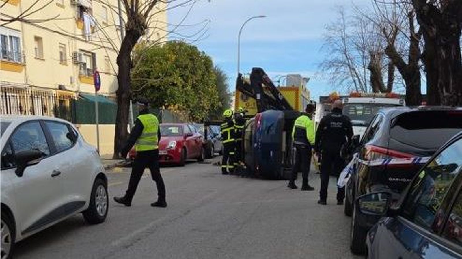 Bomberos del parque de Jerez y agentes de la Policía Local, junto al coche volcado.