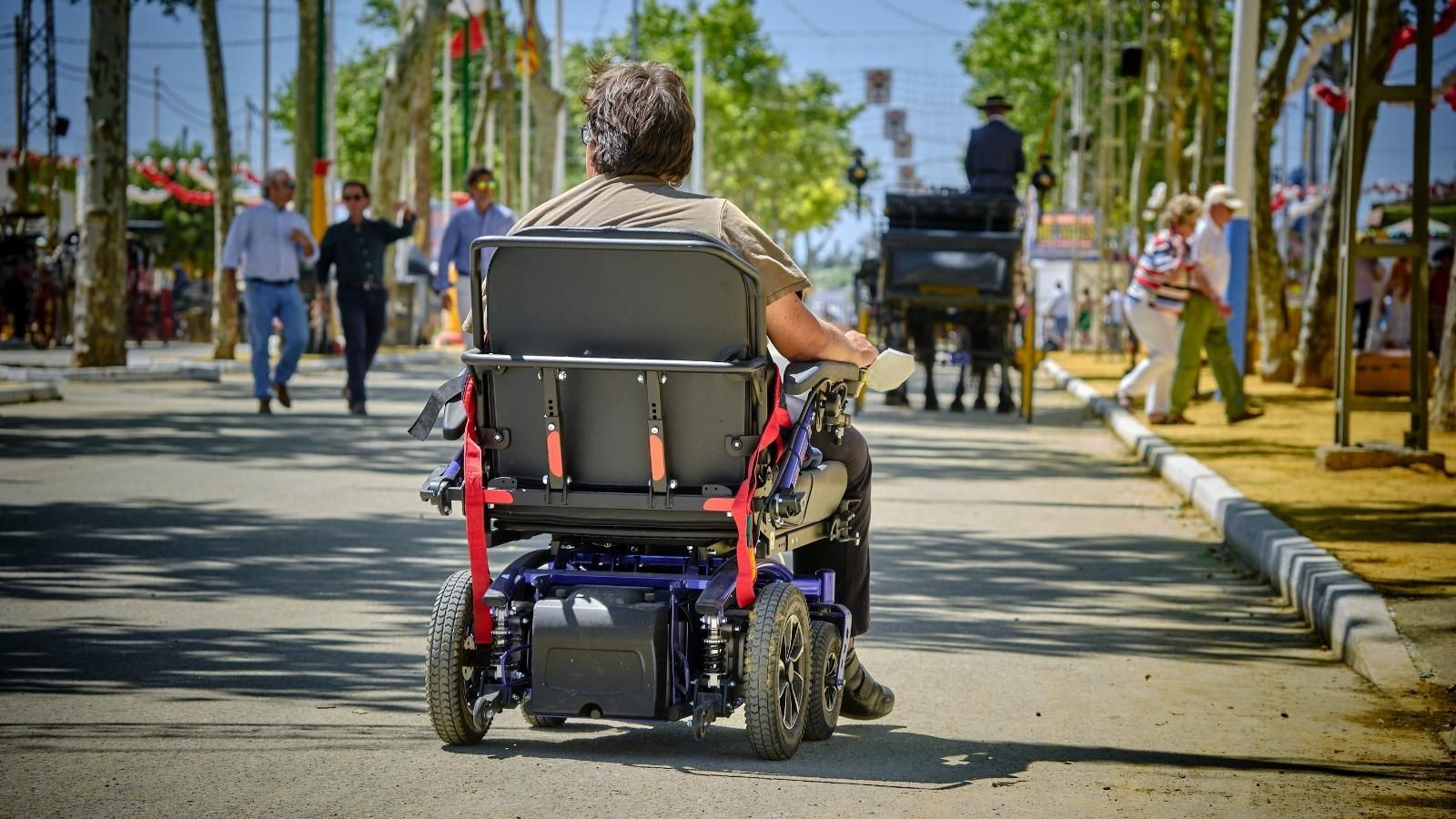 Una persona en silla de ruedas por una calle del recinto ferial de Las Banderas. Una persona en silla de ruedas por una calle del recinto ferial de Las Banderas.