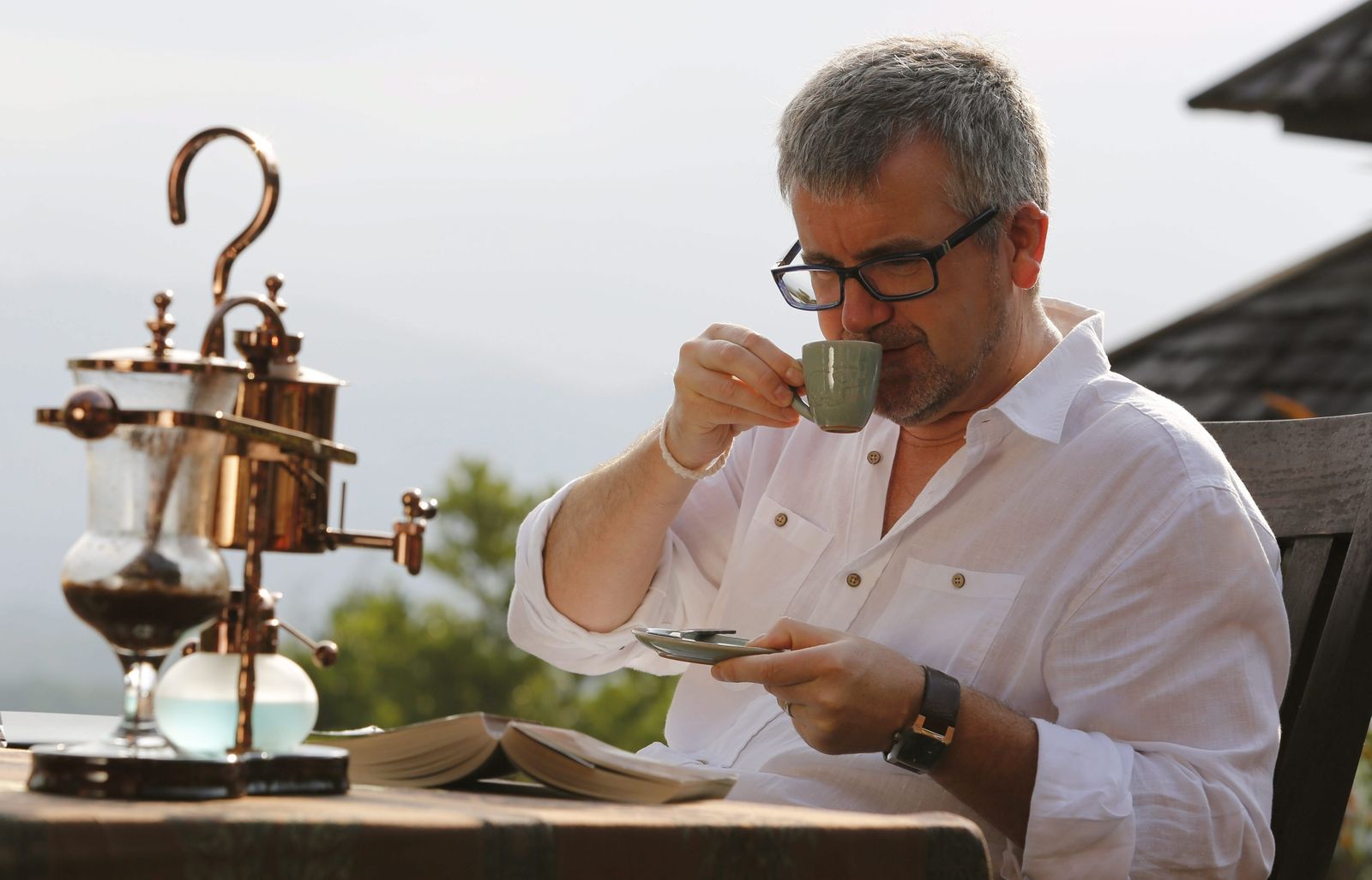 Un hombre disfruta de un café mientras lee un libro