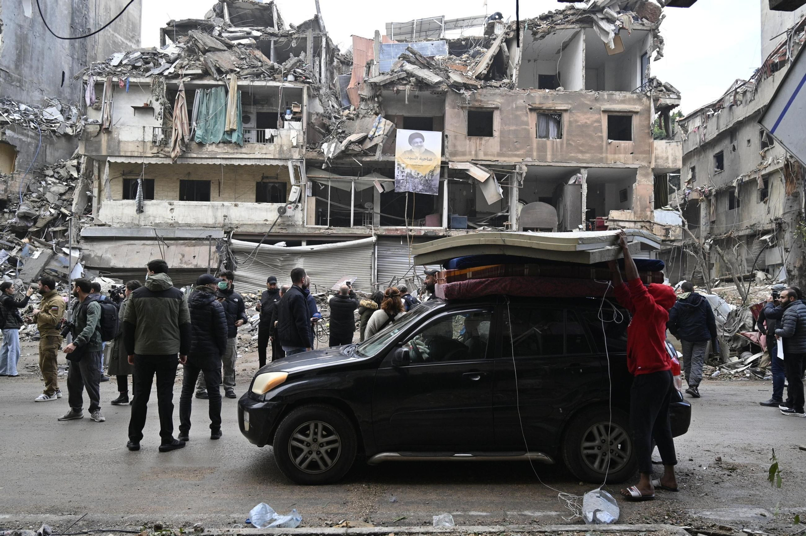 Un grupo de personas descargan sus pertenencias ante un edificio destrozado en Beirut.