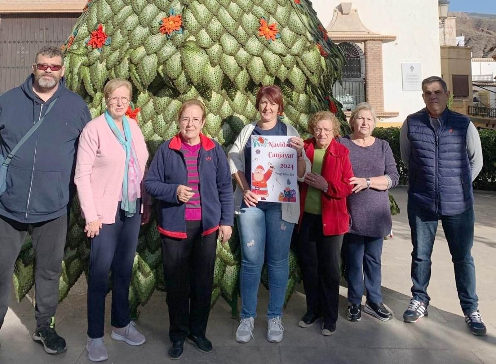 La alcaldesa muestra el rograma de Navidad junto a varios vecinos.