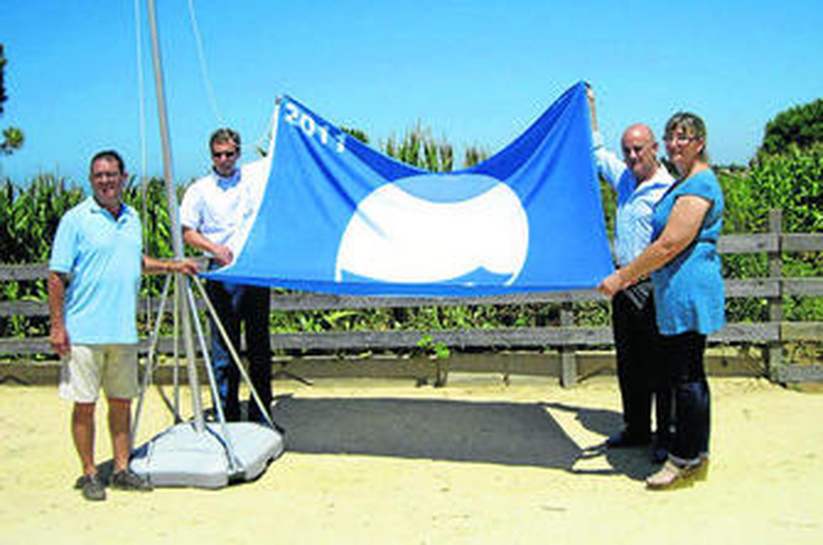 Miembros del equipo de gobierno y gestores de la instalación muestran la enseña azul.
