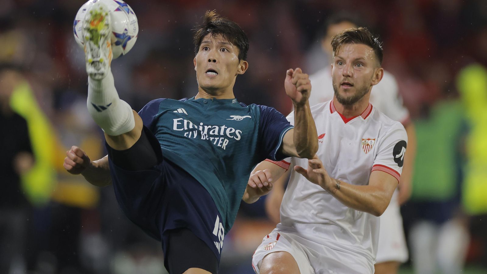 Rakitic presiona un despeje de Tomiyasu.