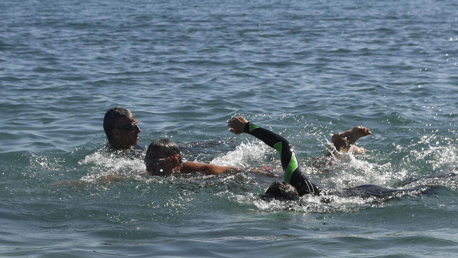 Los nadadores Manuel Carlos Peña (i), Amós Milton (c) y Antonio Huete (d) comienzan el entrenamiento en la playa de El Zapillo
