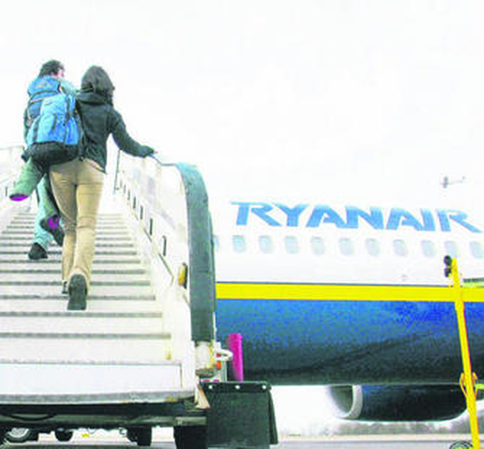 Una pareja sube a las escalerillas para acceder a un avión de Ryanair.