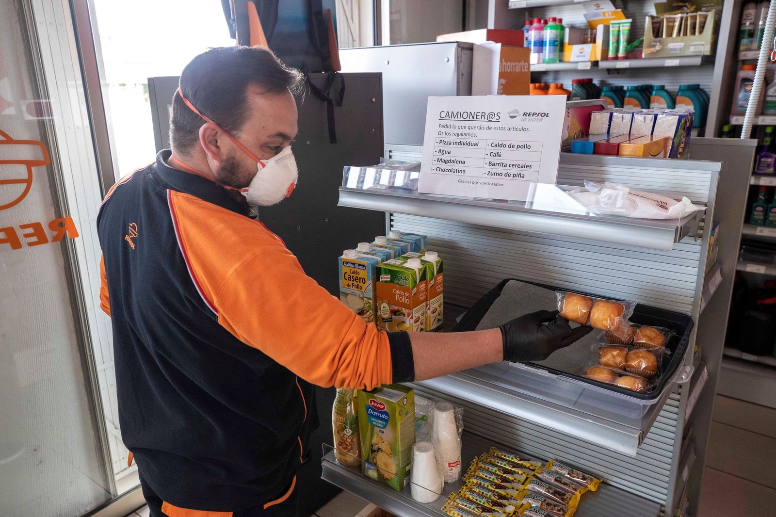 Un empleado de gasolinera coloca productos en la estantería.