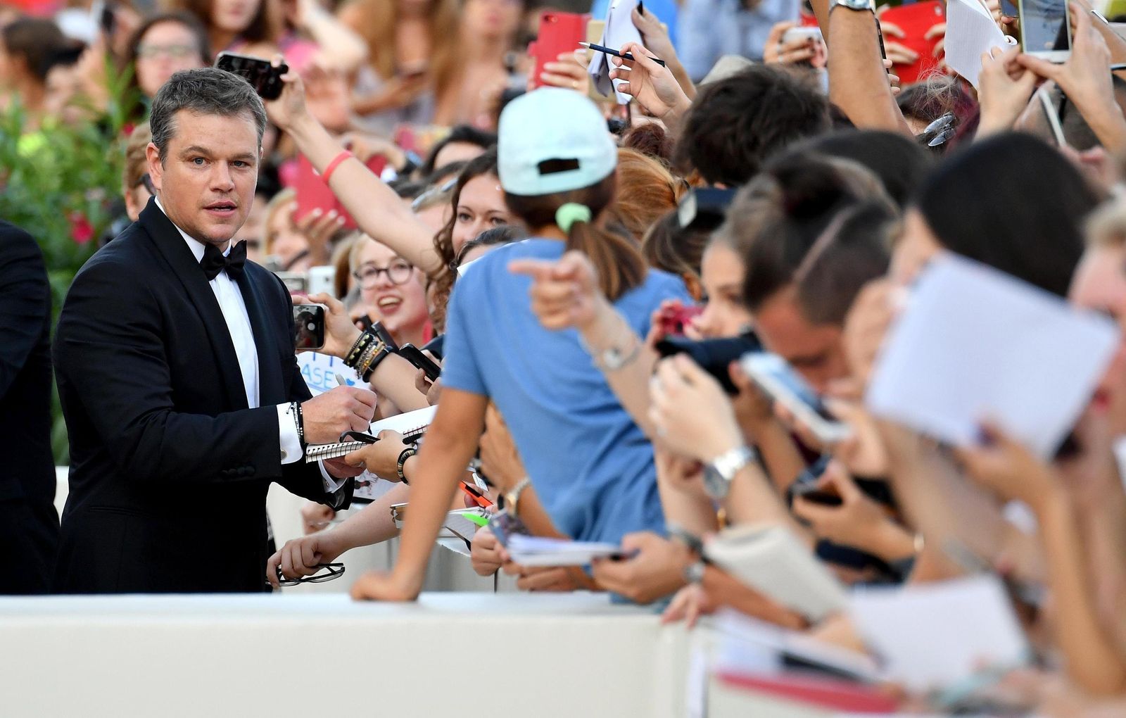 Matt Damon firma autógrafos a su llegada a la ceremonia de apertura del Festival de Cine de Venecia.