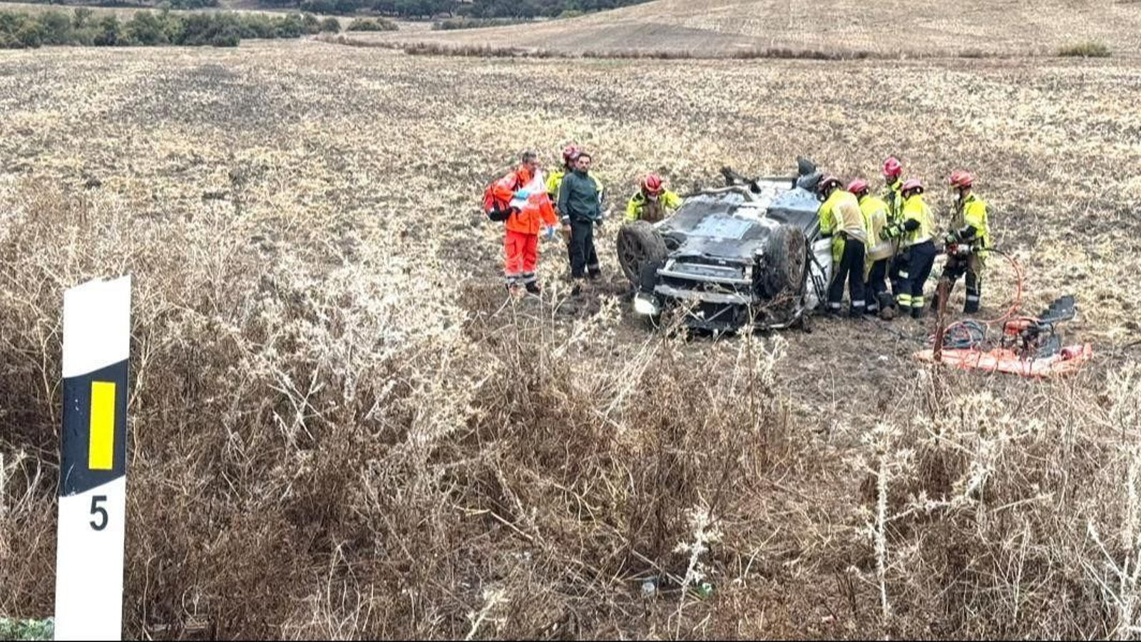 Efectivos de los Bomberos intentan sacar a la víctima del coche, que acabó completamente volcado.