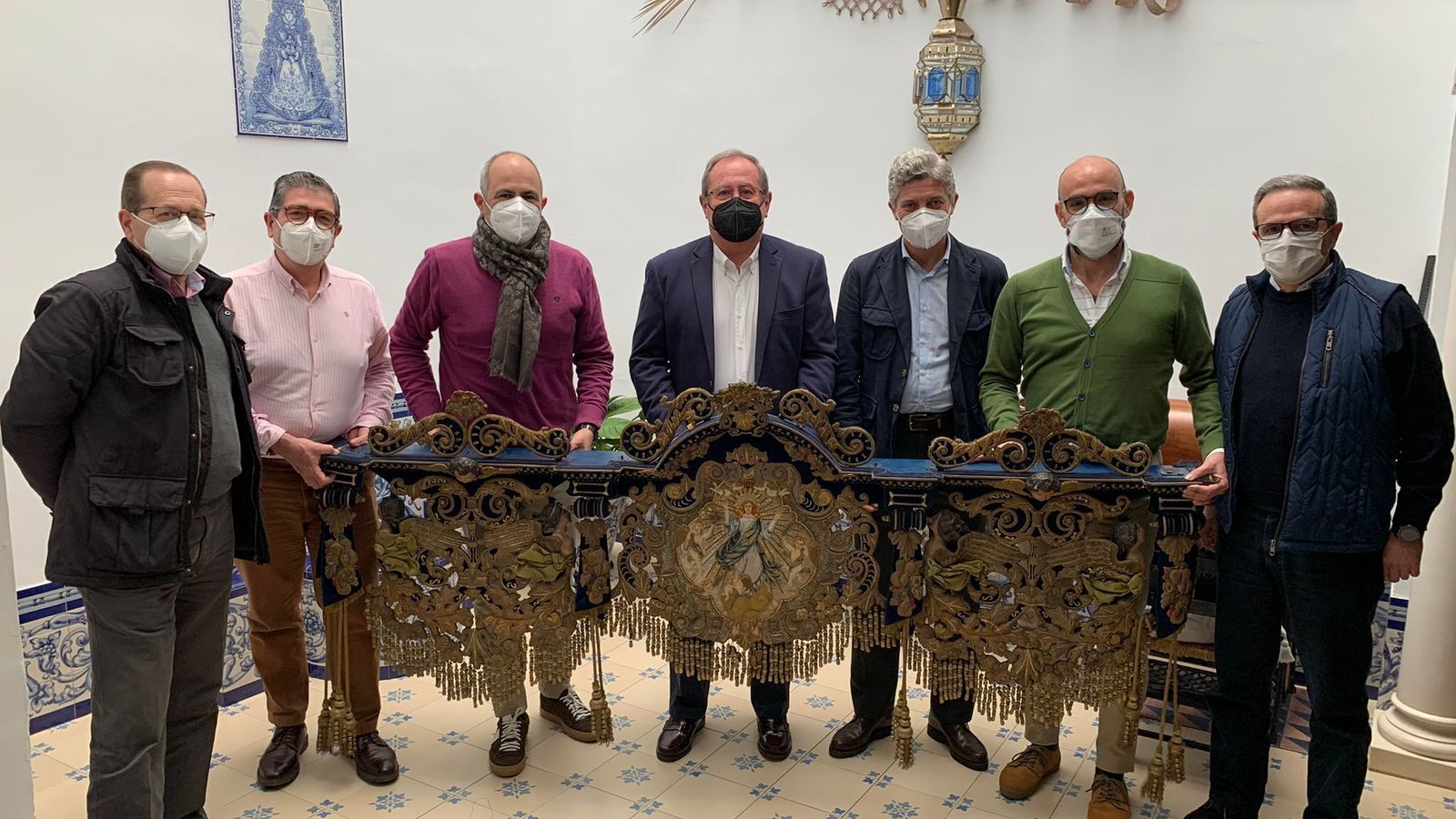 Miembros de la hermandad y el bordador con la caída delantera del palio.