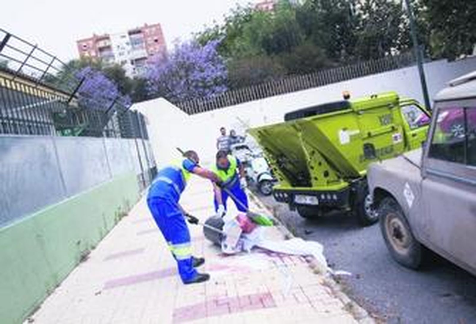 Dos operarios limpian la sangre de la víctima y retiran la sábana con que fue cubierta la víctima.