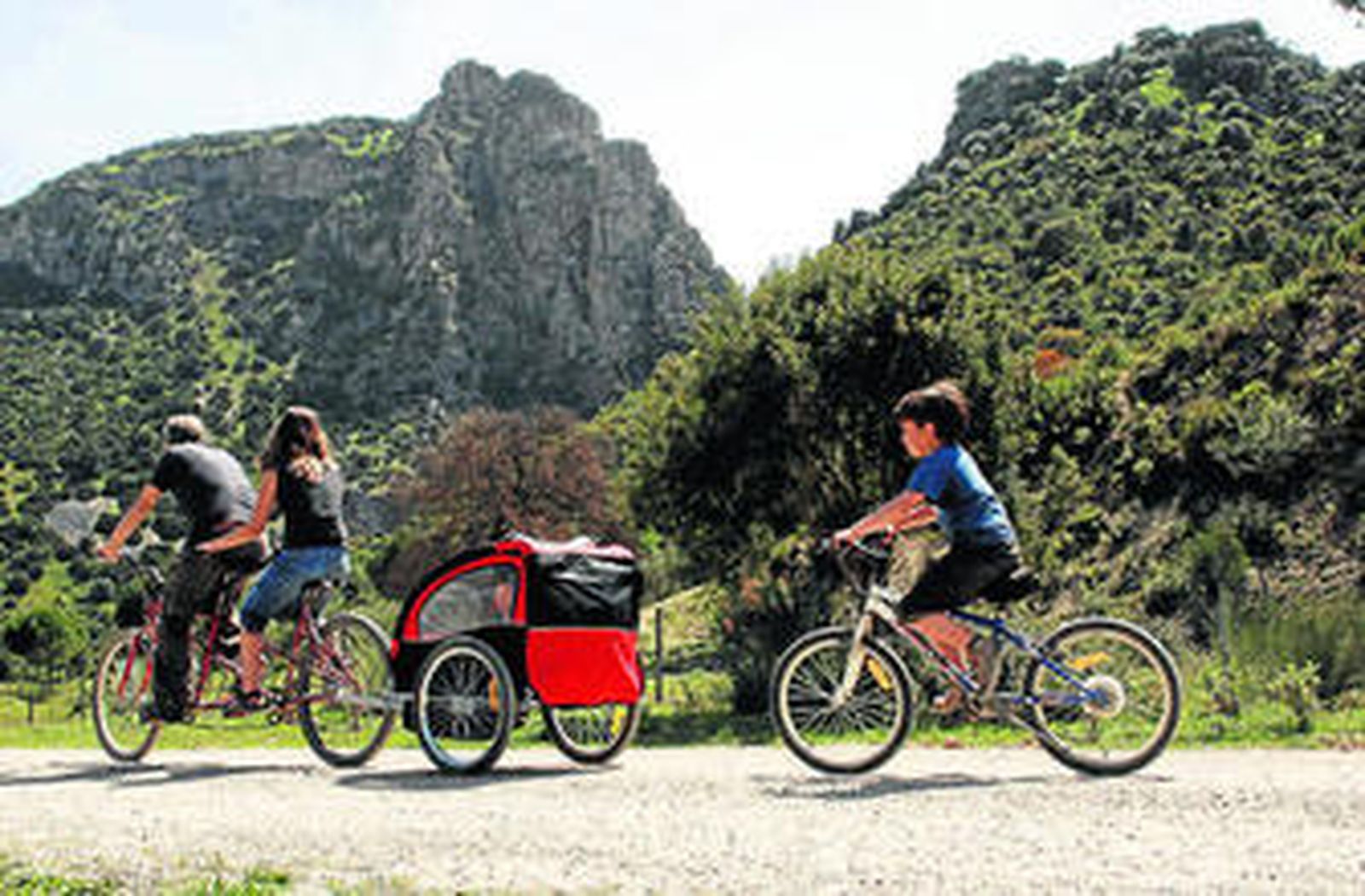 Una familia disfrutando del trazado de la Vía Verde en bicicleta.