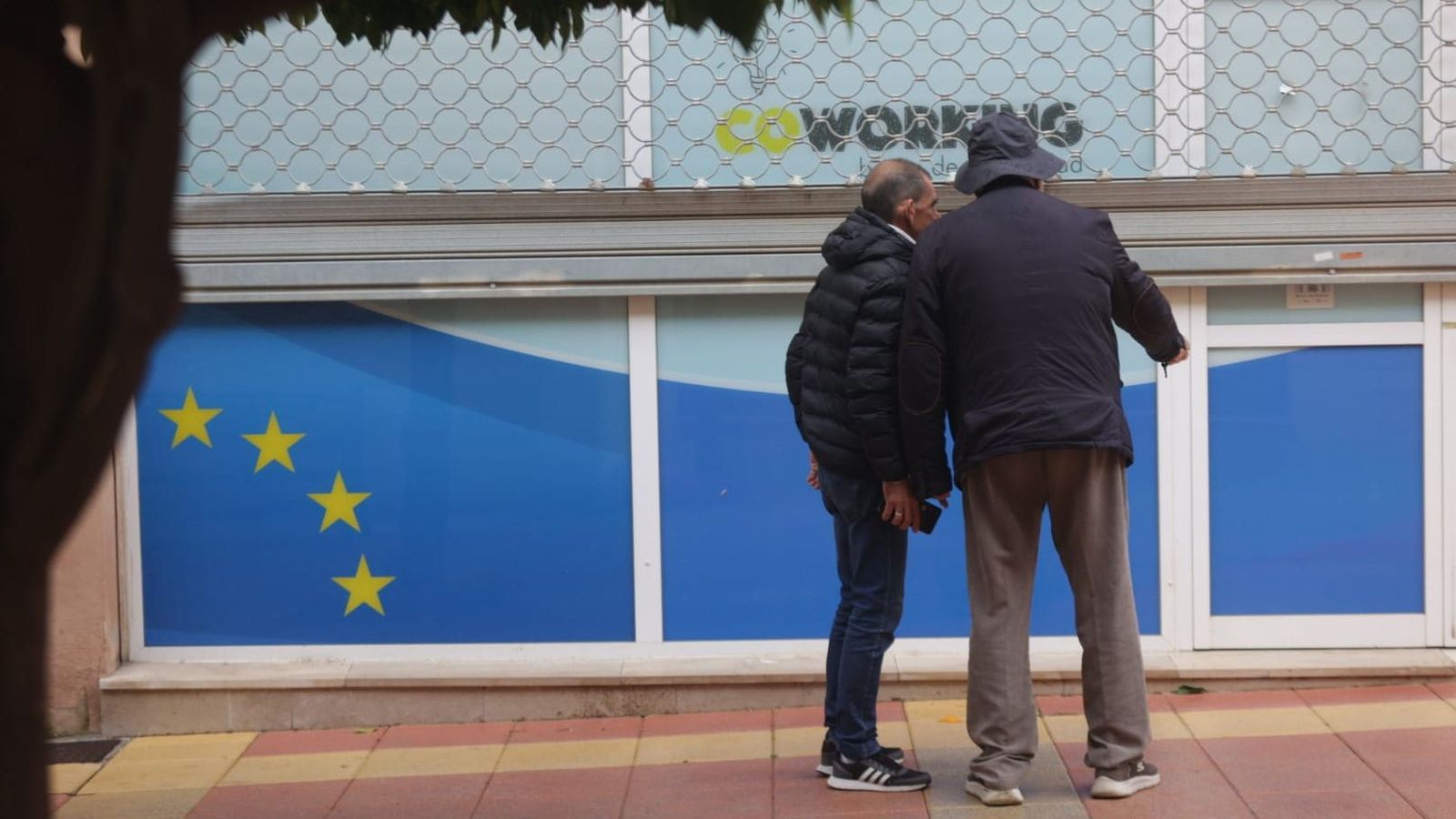 Dos personas levantan la persiana metálica del coworking La Caridad Hub para acceder al interior e inspeccionar las instalaciones este viernes por la mañana.
