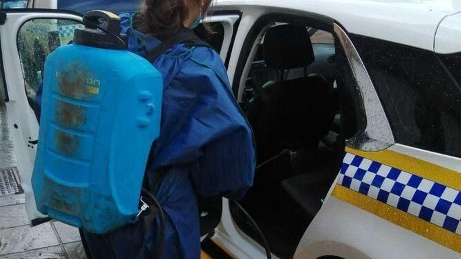 Una trabajadora desinfecta uno de los patrulleros de la Policía Local de San Juan de Aznalfarache.