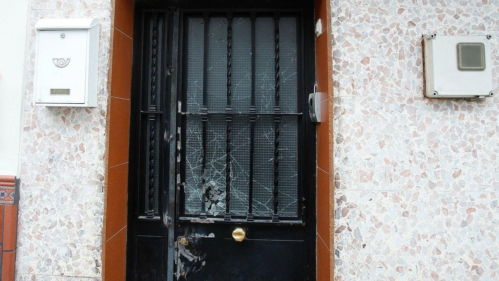 Detalle de la puerta de una de las viviendas, con tres cerraduras y el cristal destrozado.