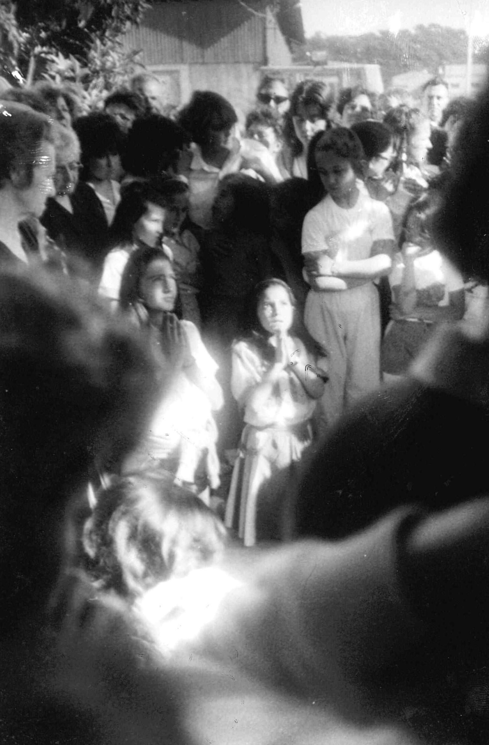 Dos niñas rezan arrodilladas ante el árbol de la estación de trenes en El Repilado.