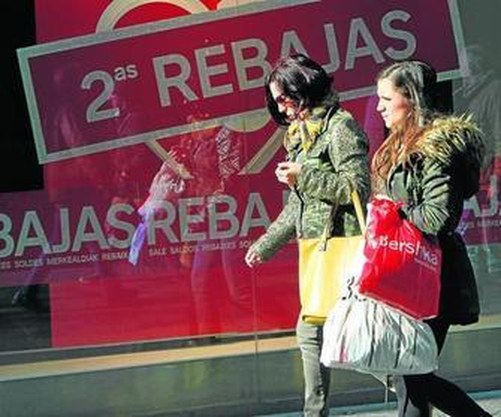 Dos mujeres por una céntrica calle de Sevilla con bolsas de compras.