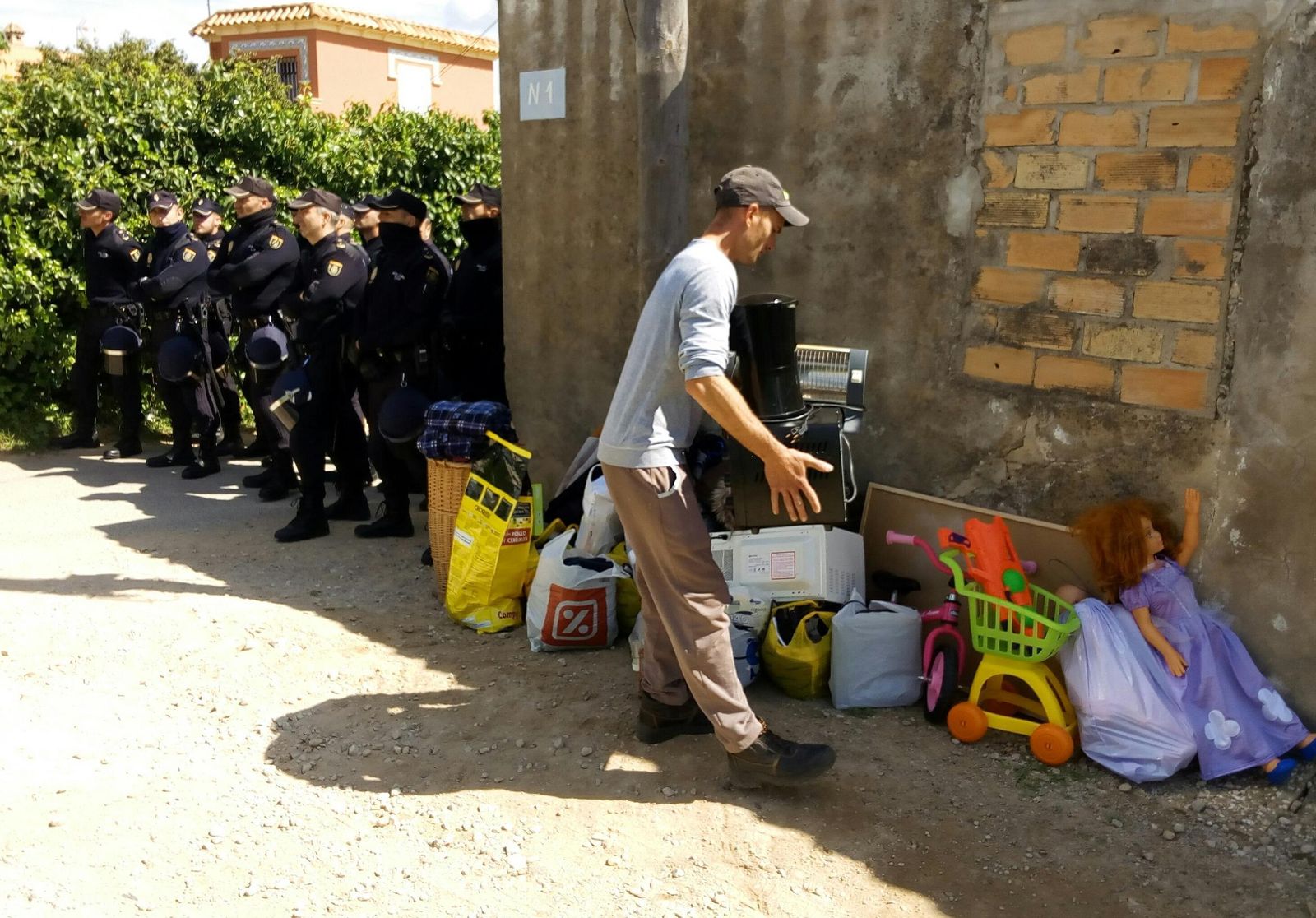 Uno de los afectados retirando sus enseres en presencia de agentes antidisturbios.