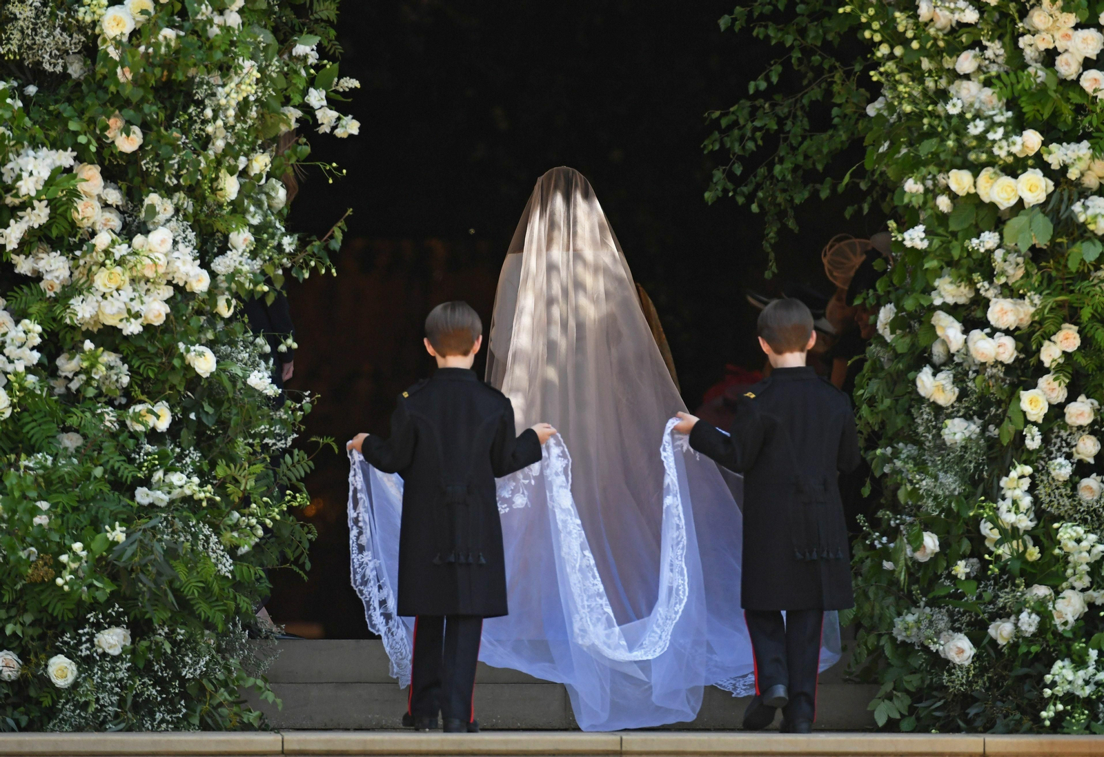 Un par de niños sostienen el velo de una novia durante la celebración de una boda.