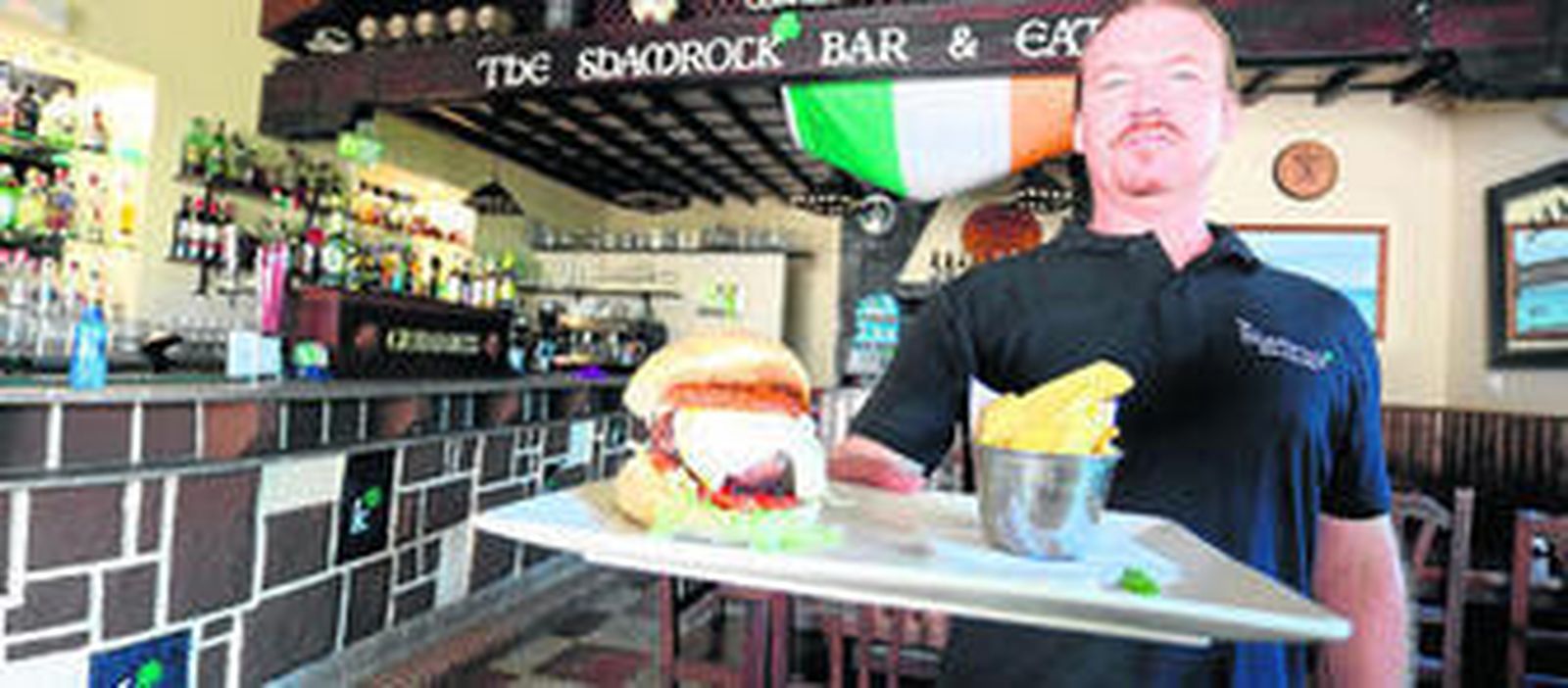 Steve, el responsable del Shamrock, presenta la gran hamburguesa que ofrece en su local.