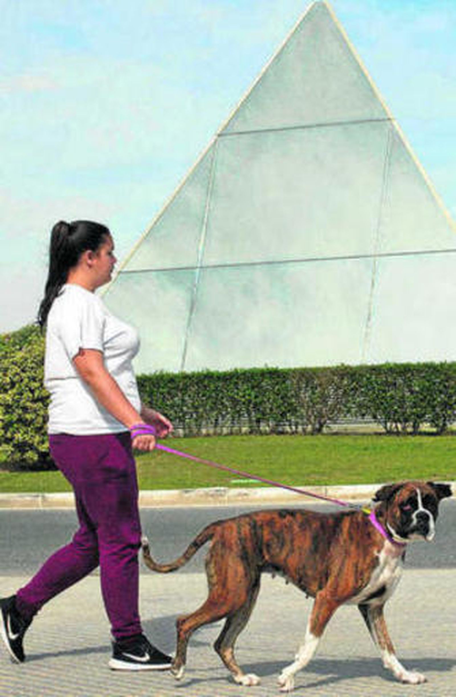 Una vecina pasea con su perro junto a la pirámide de Alburquerque.