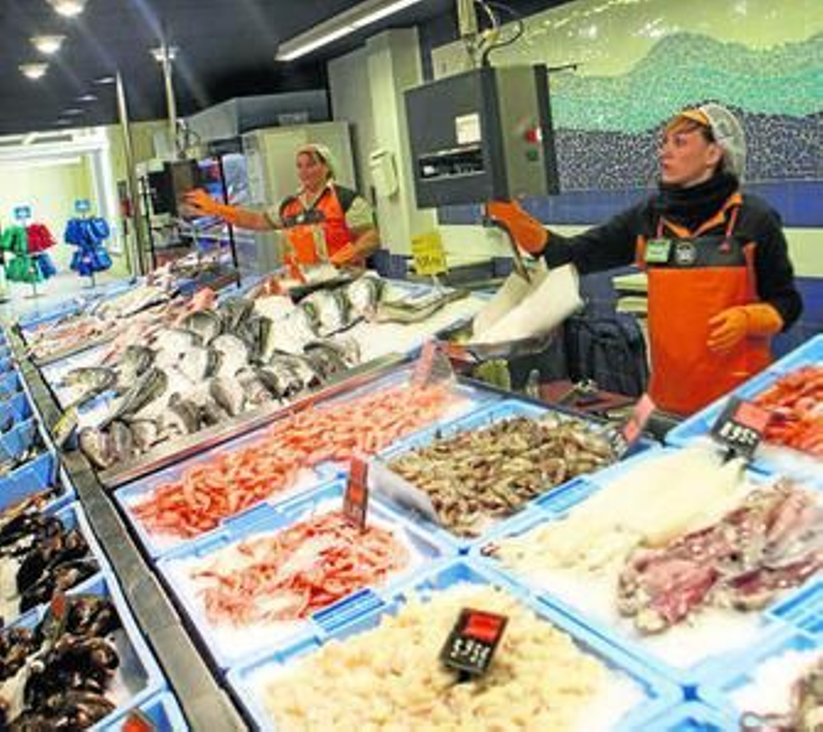 Dos empleadas del supermercado de Sotogrande atienden la sección de pescadería, el pasado martes.
