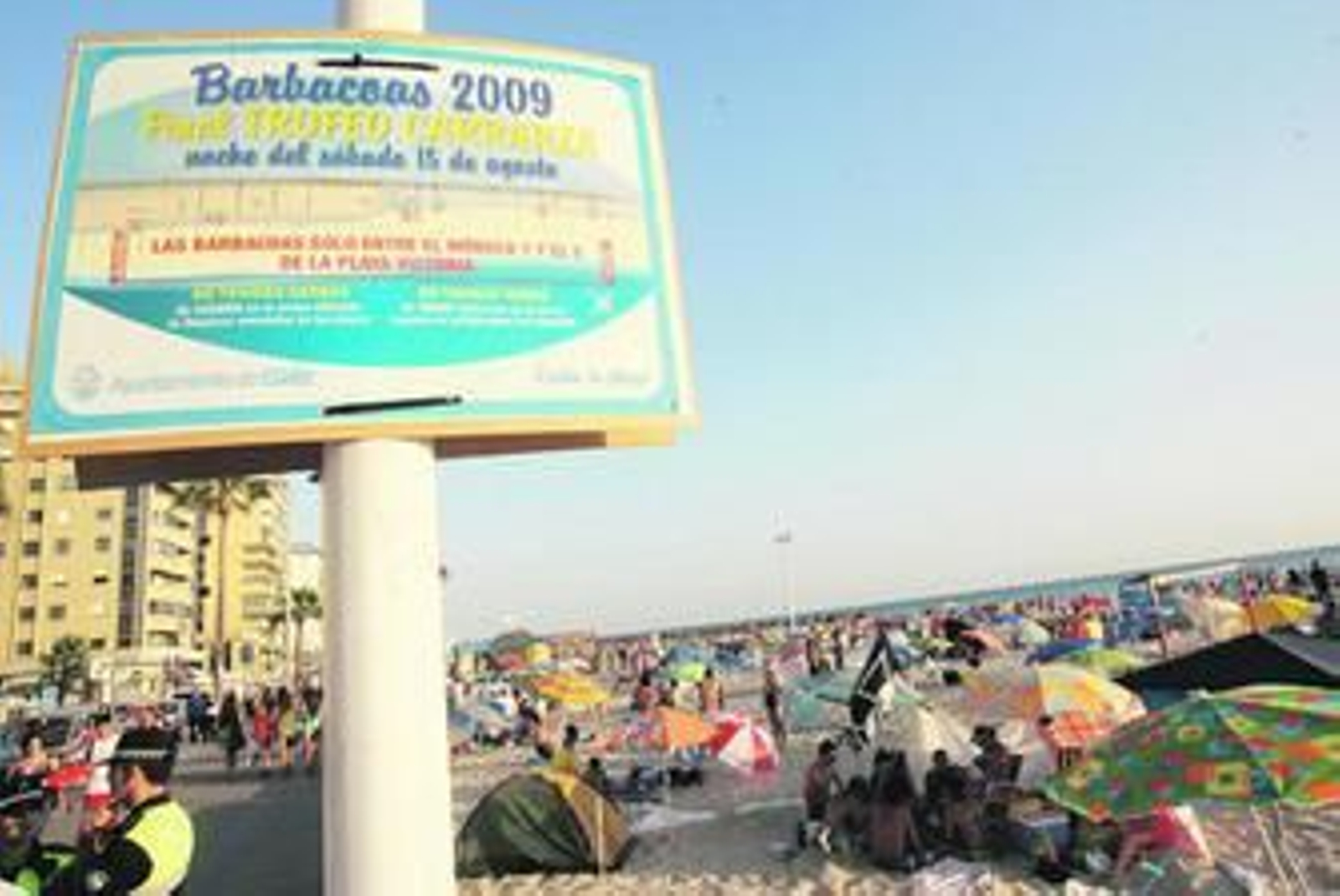 Un cartel anuncia la celebración de las barbacoas 2009 a pie de playa.
