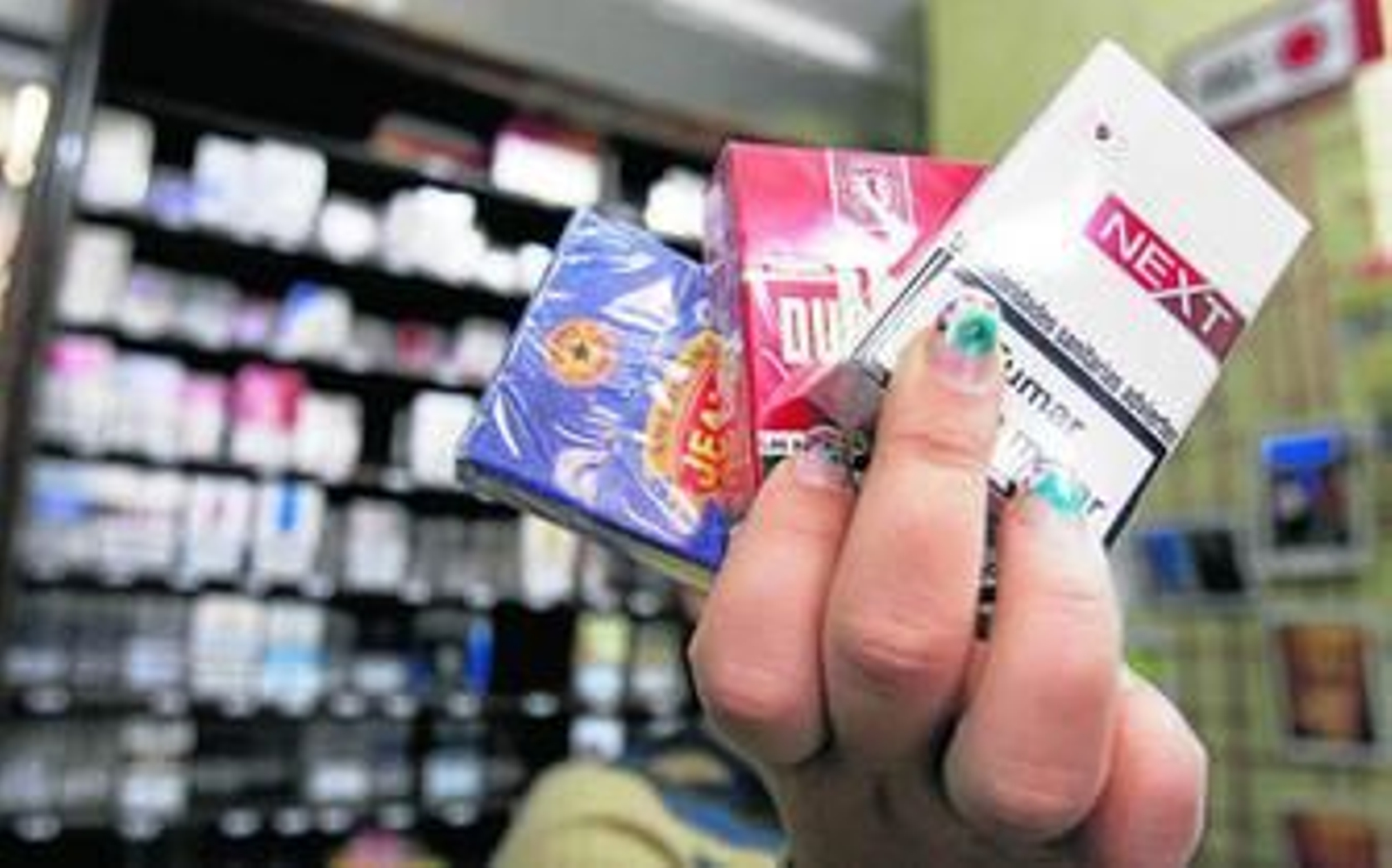 Una estanquera muestra varias cajetillas de cigarrillos.