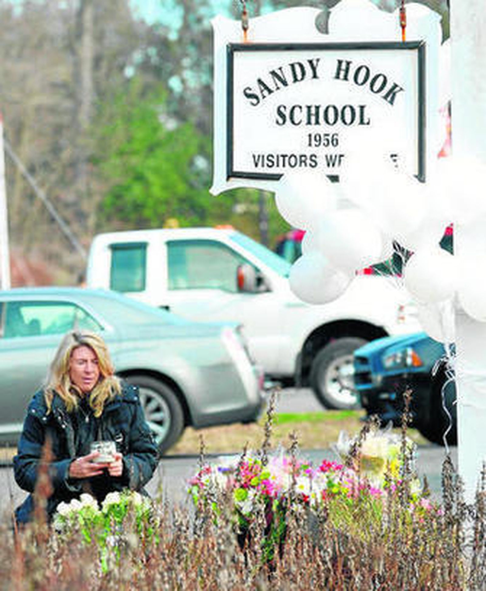 Una mujer sostiene una vela y reza junto a la entrada de la escuela de Newtown.