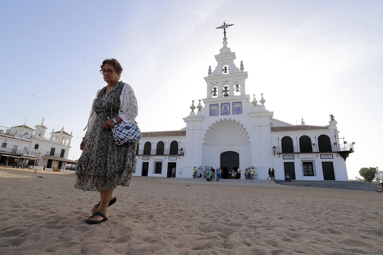 Una mujer camina ante la ermita de la Virgen del Rocío.