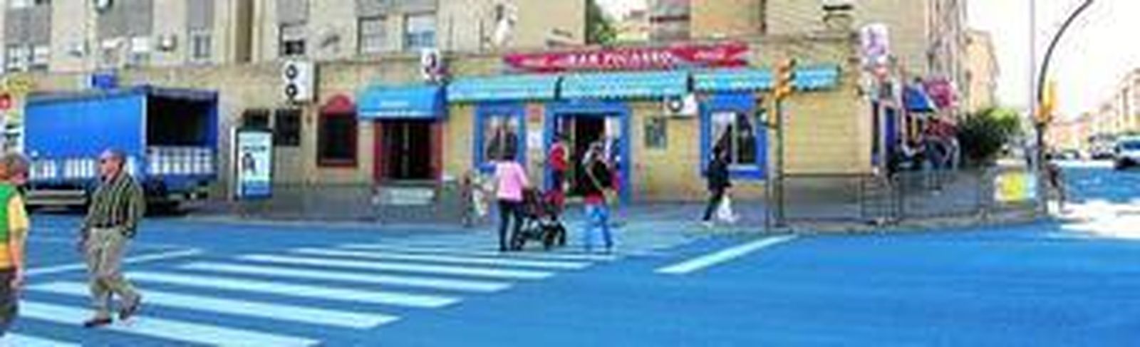 Paso de peatones de la avenida Galaroza, en su esquina con Palomeque, la vía principal del barrio, con uno de sus establecimientos más conocidos, el bar Picasso, al fondo.