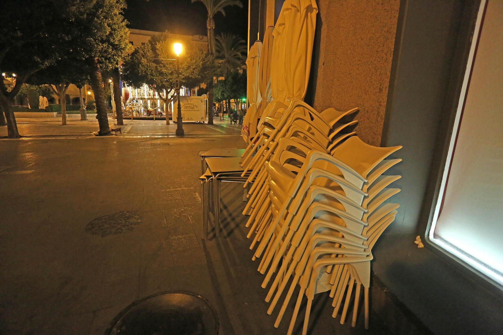 Sillas apiladas ante un bar al momento del cierre.