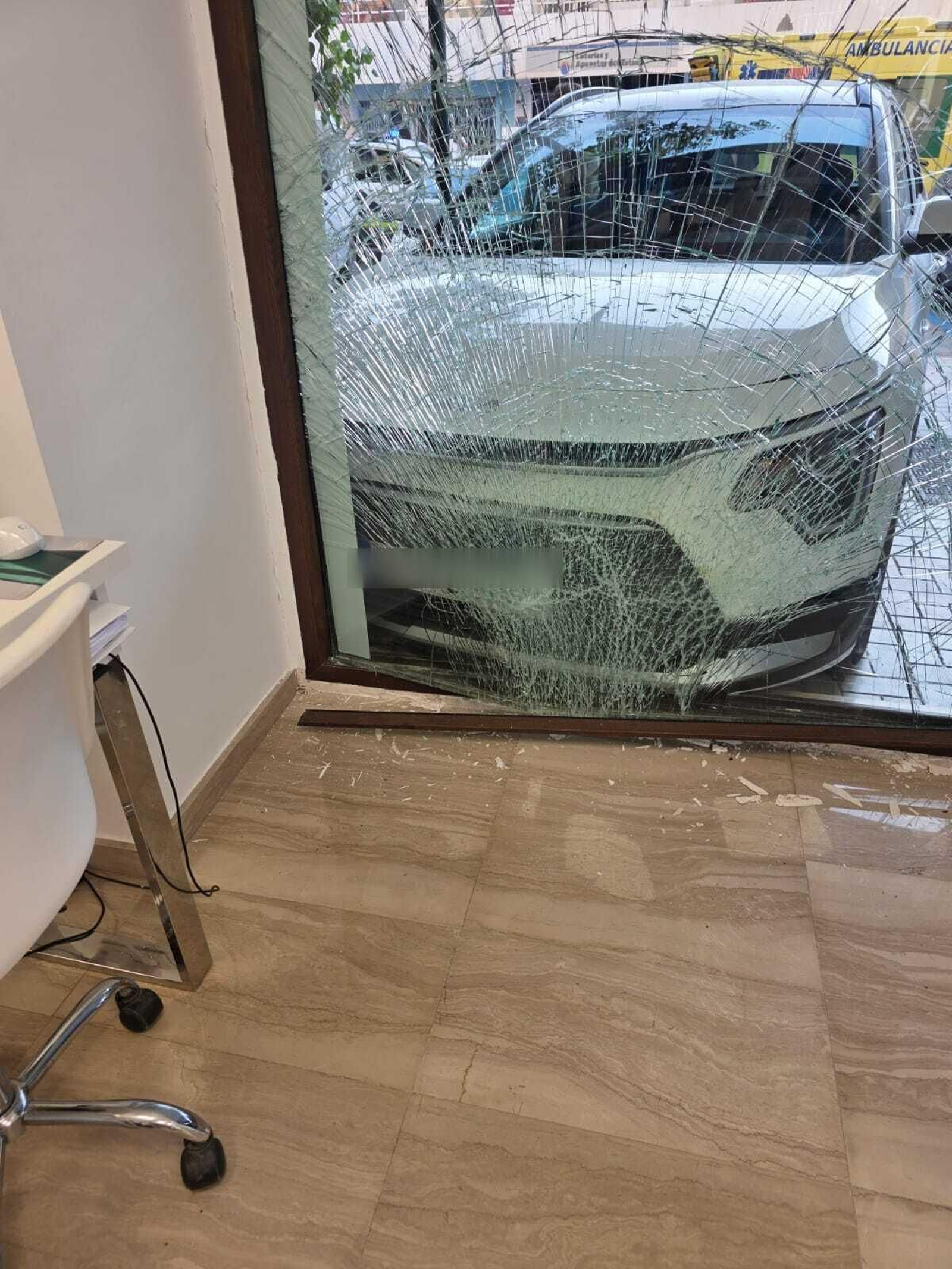Momento en el que un coche se estrella contra el escaparate de una óptica de Málaga