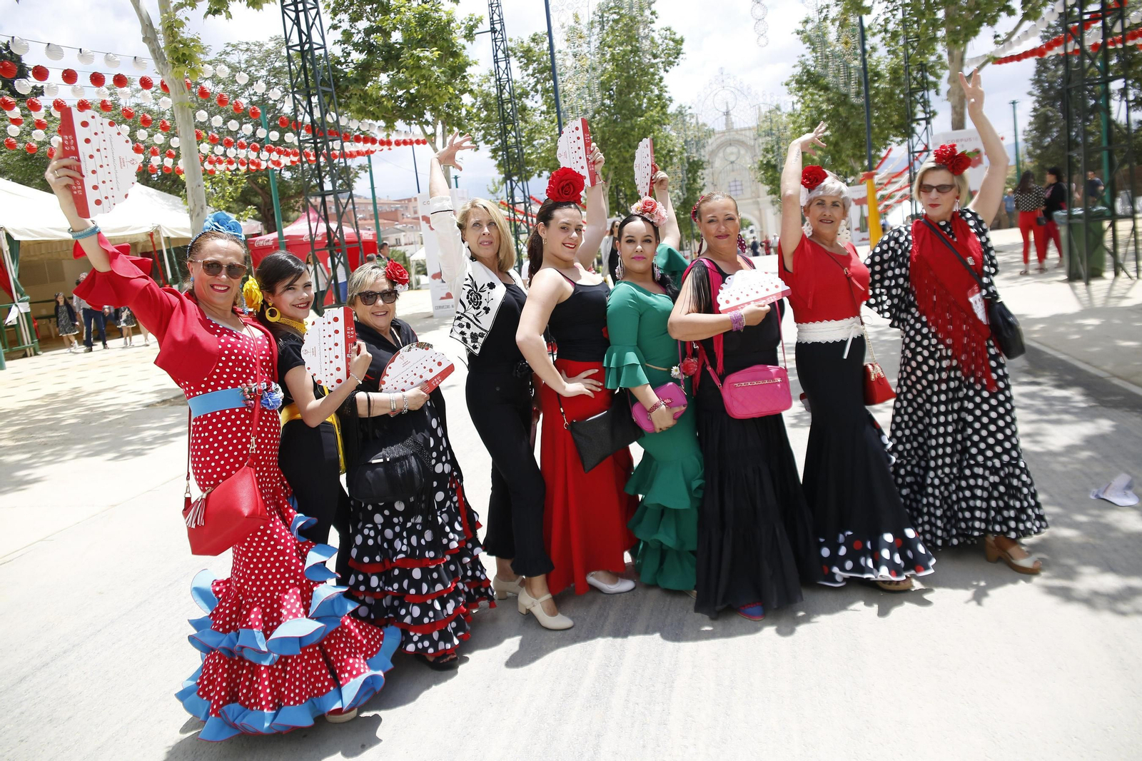 Varias mujeres posan vestidas de flamenca en la calle principal de un recinto ferial que ayer estaba atestado de personas.