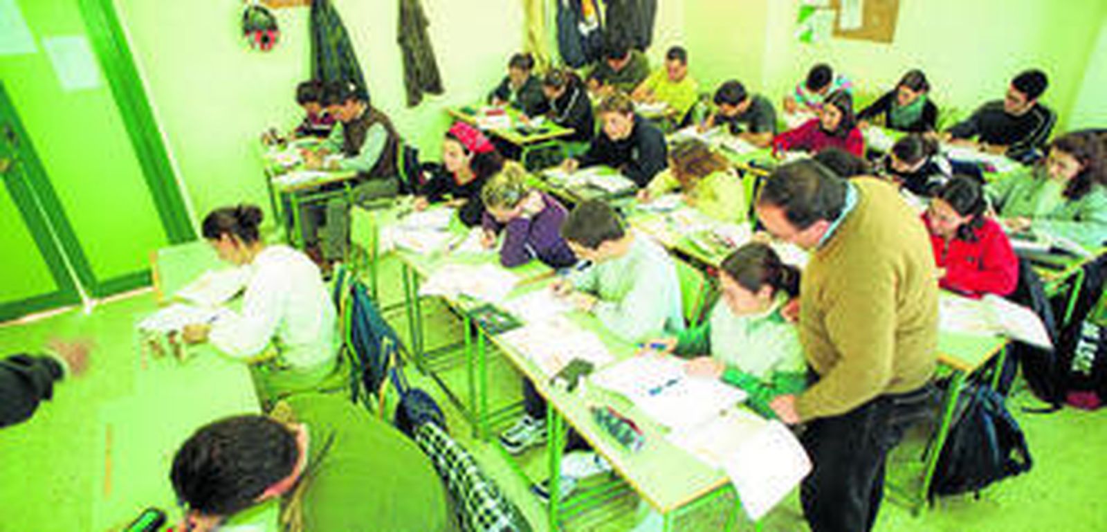 Alumnos realizan tareas en clase bajo la supervisión de su profesor.