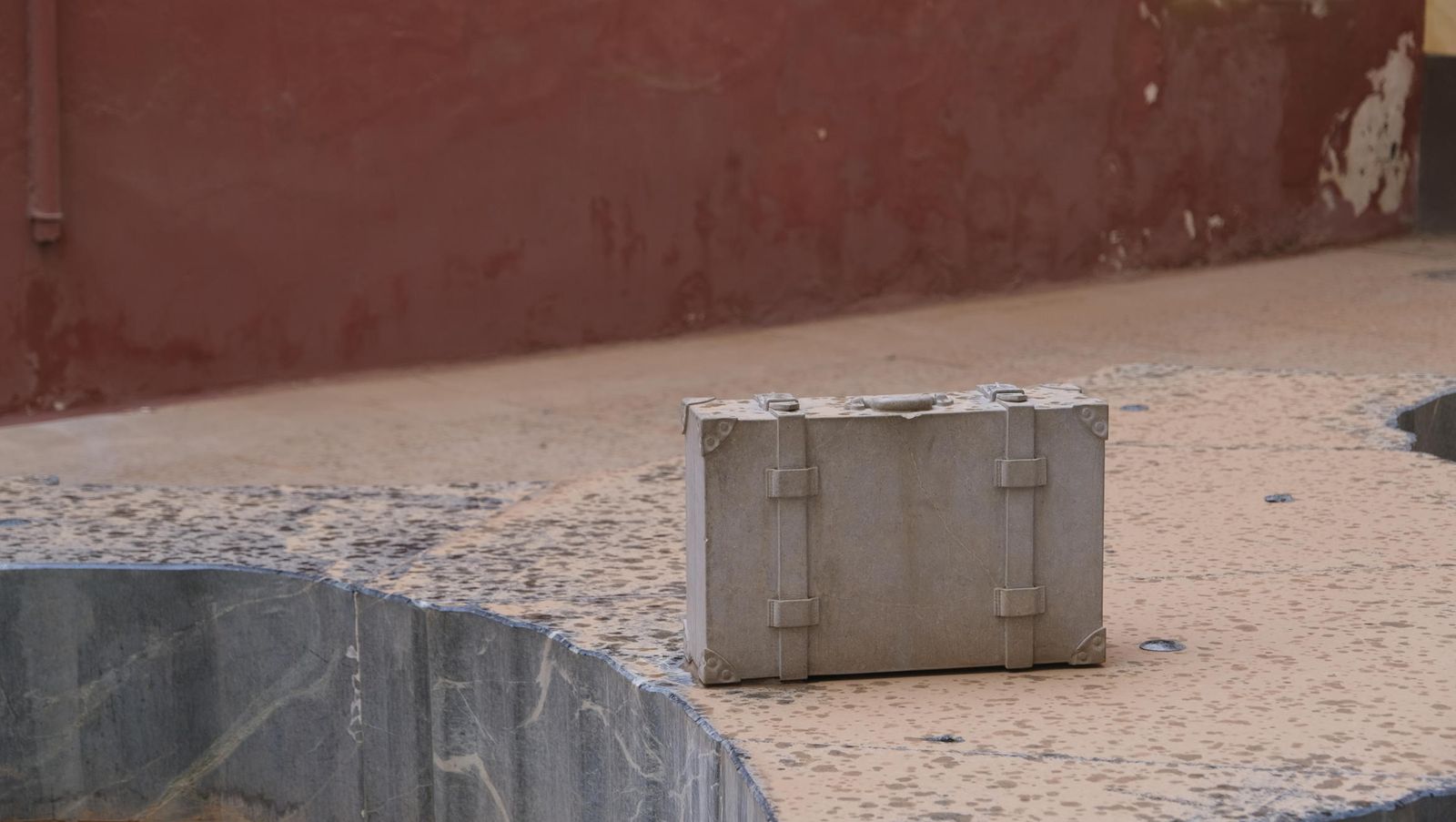 La solitaria maleta sin su propietario  descansa sobre el banco con la forma de la provincia de la plaza Calderón.