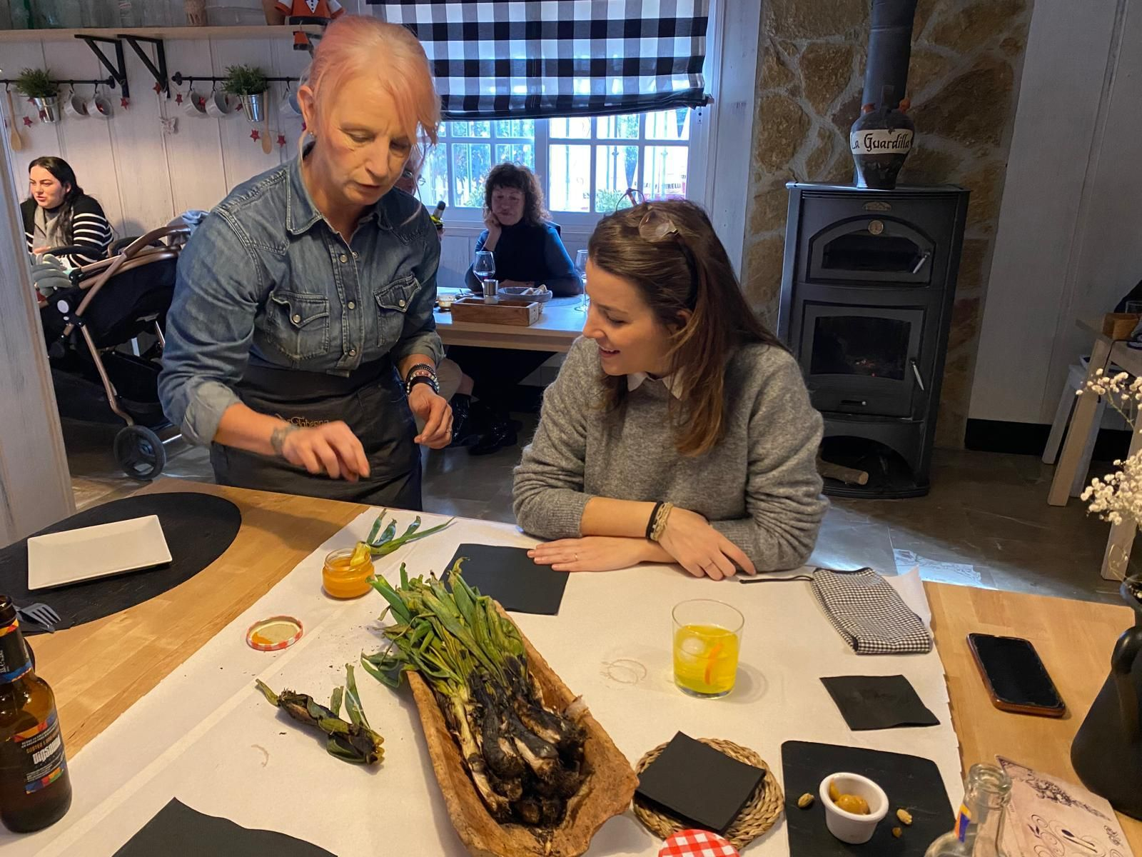 Pilar de Cózar, mostrando cómo comer los calçots a una clienta del restaurante.