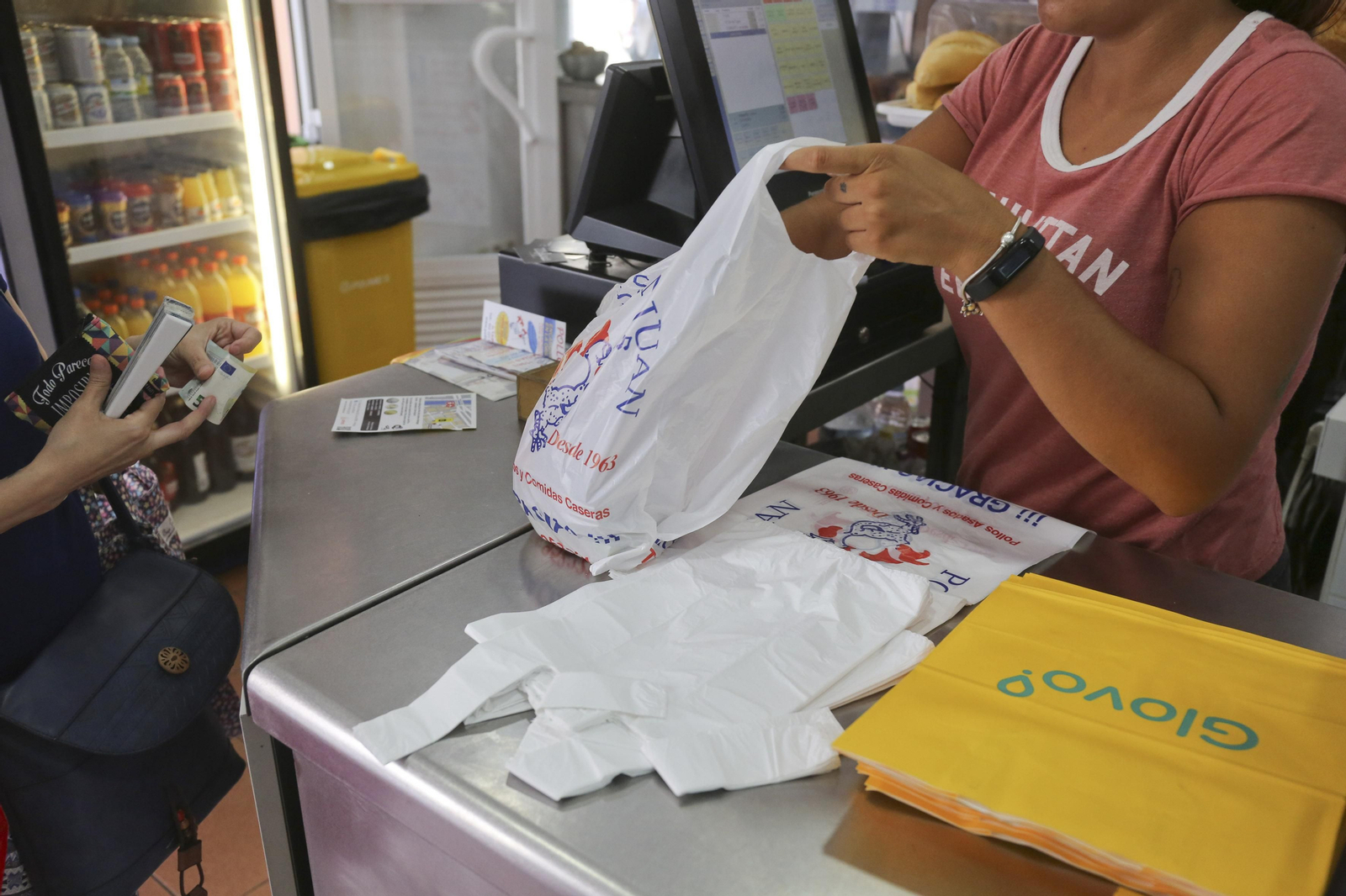 Una empleada de Pollos San Juan coloca una ración de comida en una bolsa de plástico.