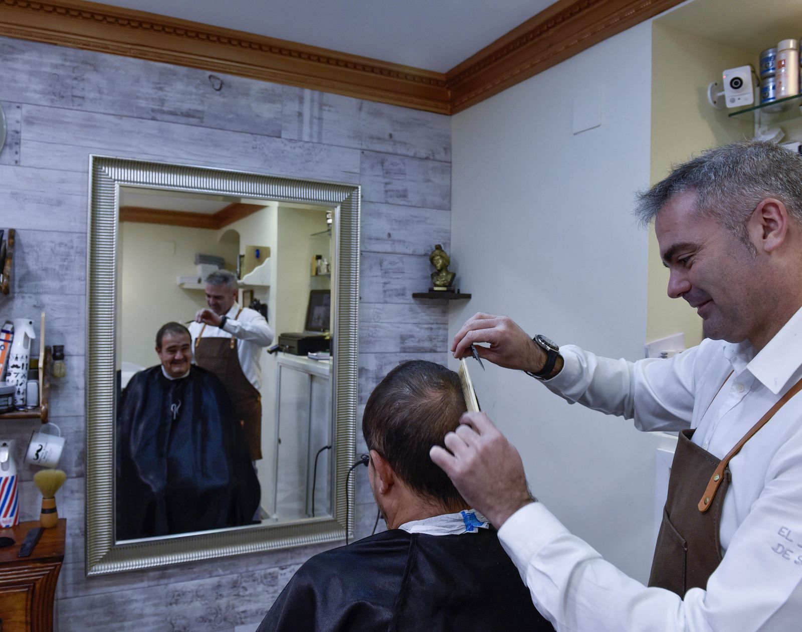 Rubén Olmo peina a un cliente en El Barbero de Sevilla, abierto desde hace tres años en la calle O'Donnell.