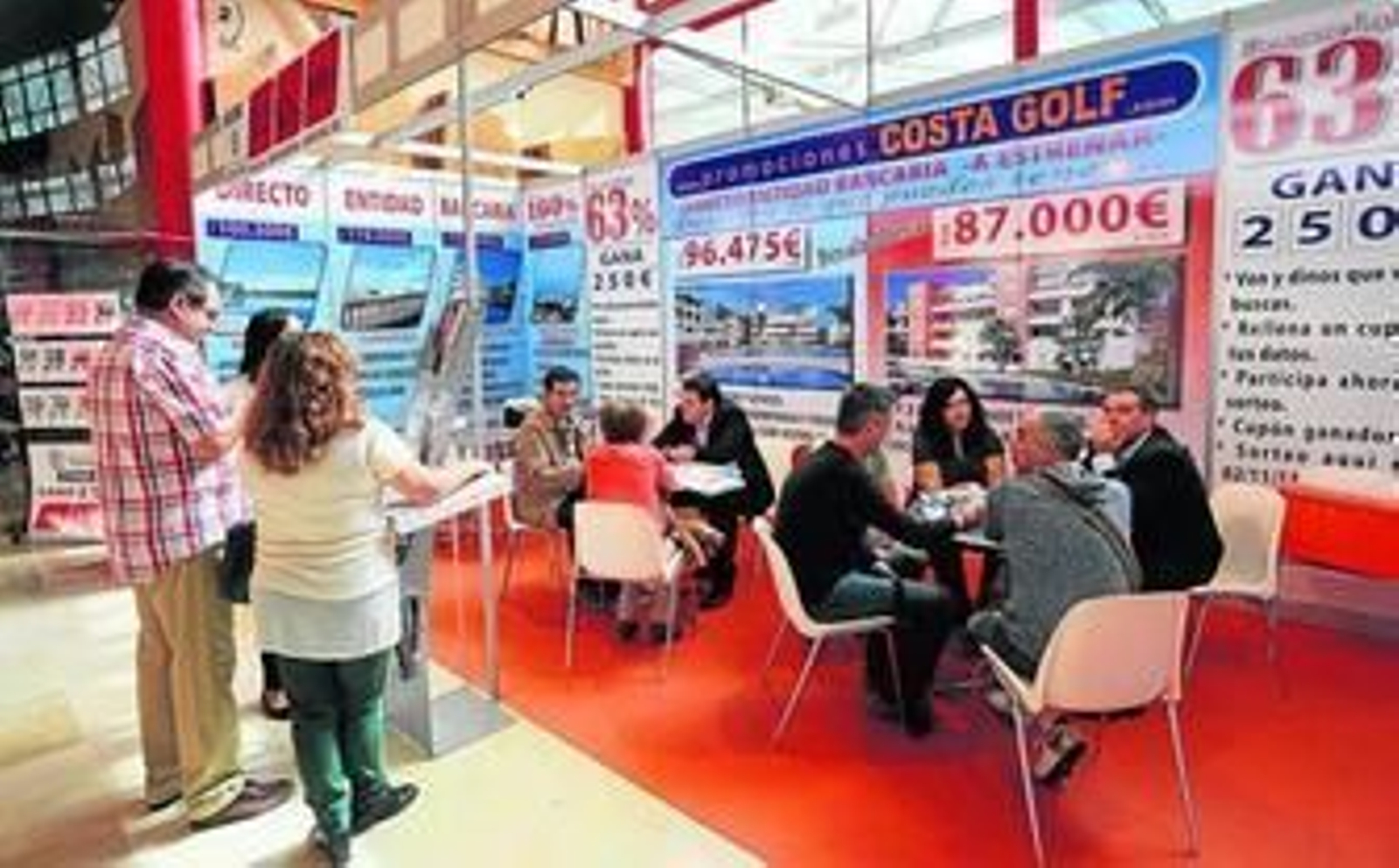 Varias personas en el expositor de una promotora inmobiliaria en una feria en Málaga.
