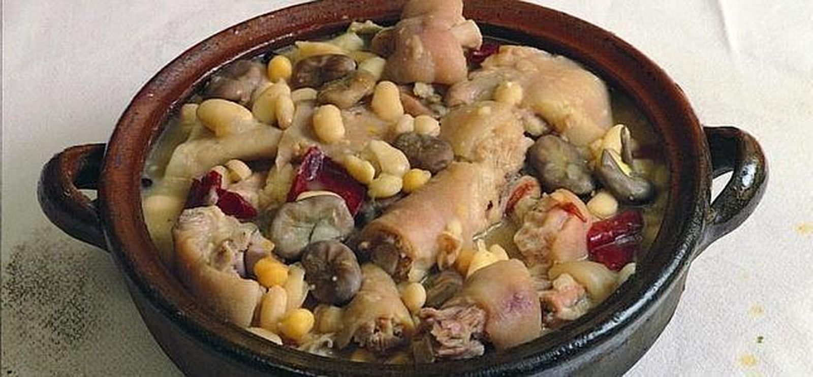 El principal ingrediente de este plato típico lo aportan diferentes partes del cerdo (manos, orejas, rabo, costillas y tocino)