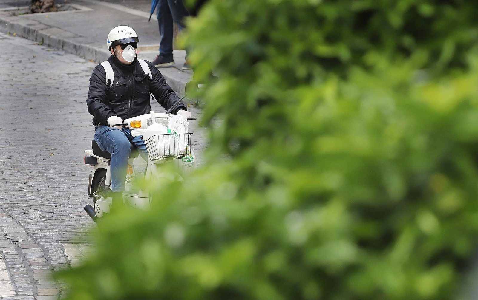 Un hombre conduce en moto con mascarilla.