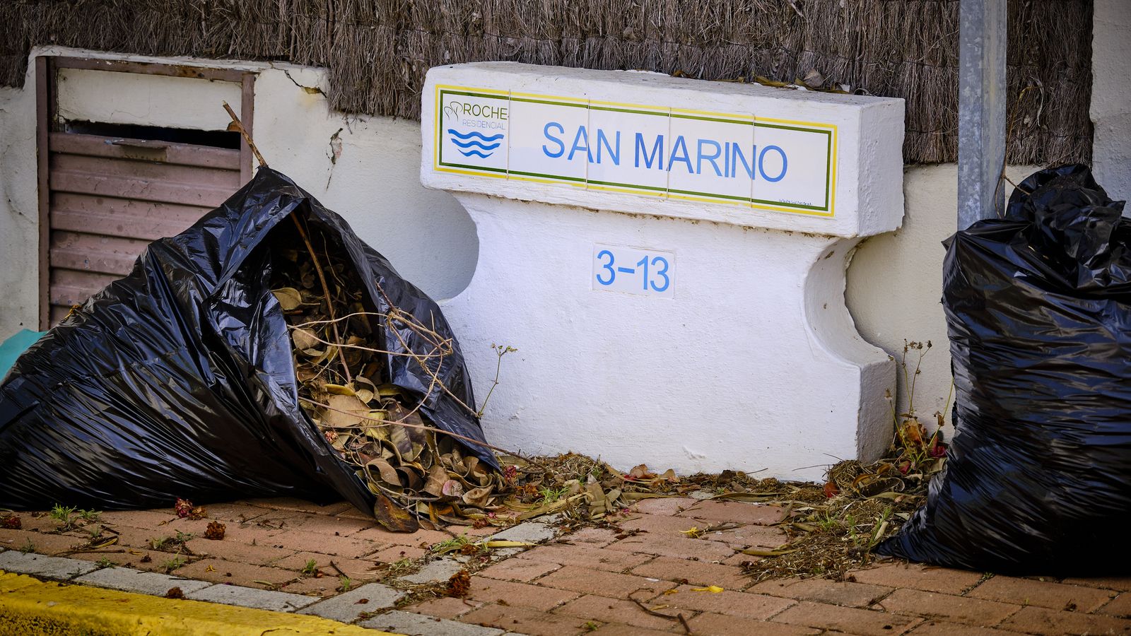 Bolsas de basura y restos de poda, acumuladas en una de las calles de la urbanización.