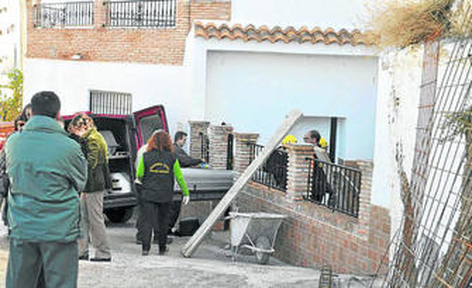 Los servicios funerarios sacan de la vivienda uno de los féretros.