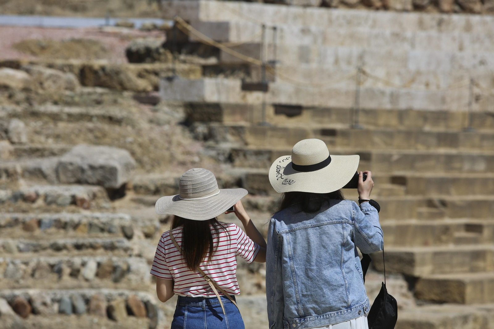 Dos turistas se protegen del sol con un sombrero.