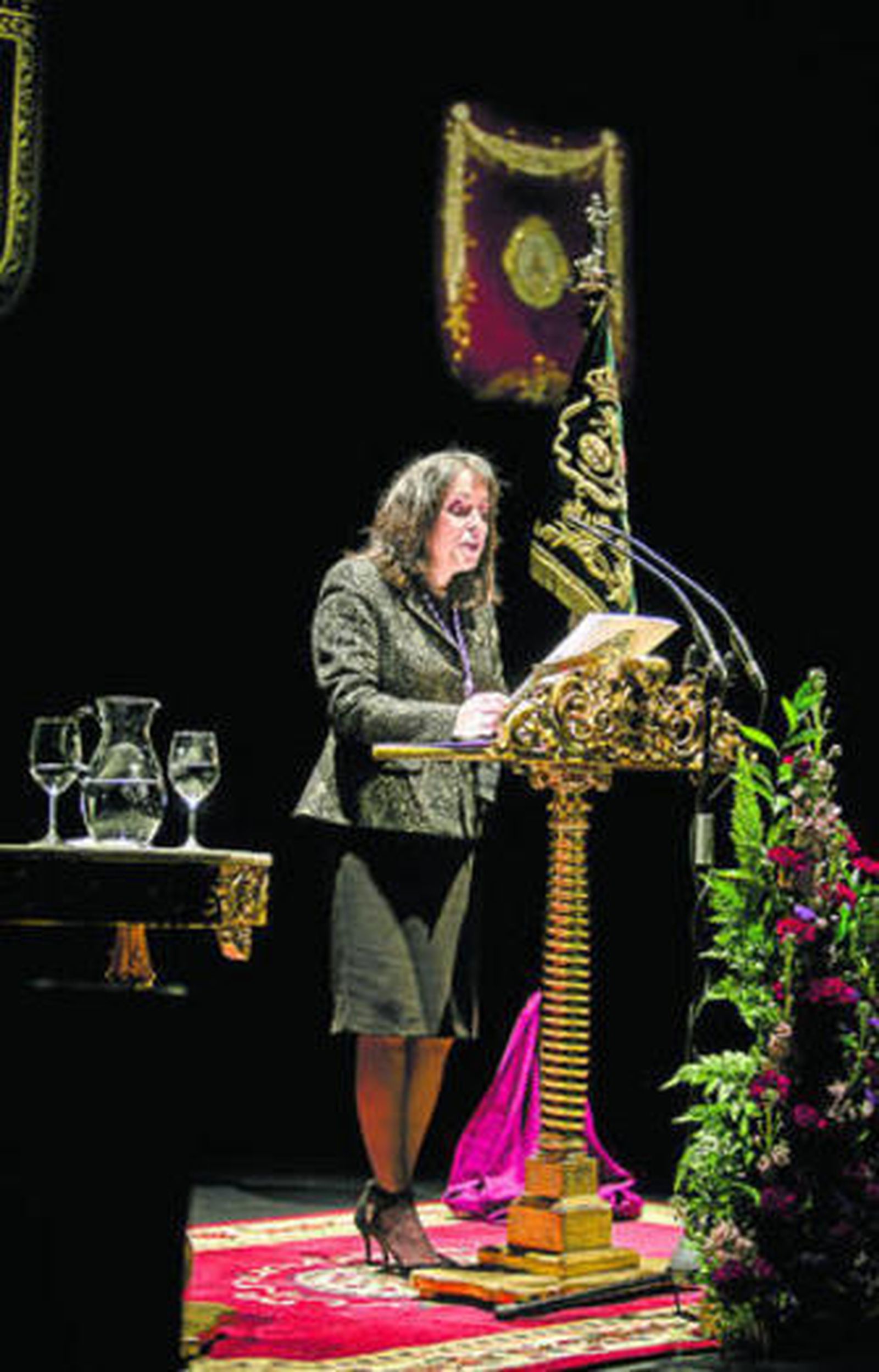 La pregonera, Rosa María Cossi, se dirige a los cofrades desde el atril del Gran Teatro Falla.
